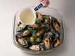 Photo of puring wine over mussels