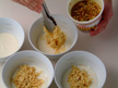Image of dividing white sauce and noodles into 4 serving bowls.