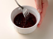 Photo of mixing ingredients of raspberry sauce in a small bowl.