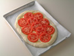 Image of the pizaa topped with tomato slices.